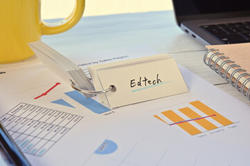 There's a word book on a desk with a cup of coffee and laptop pc. The word Edtech is written in it....