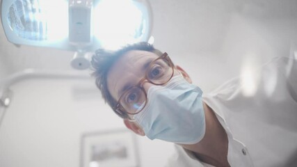 Dentist smiling and doing thumbs up to patient after successful mouth surgery procedure. White male dentist looking down on person after fixing his teeth and health. Pov of Happy dental doctor