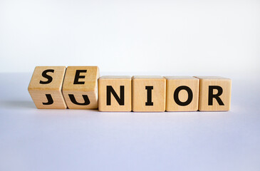 From junior to senior symbol. Turned cubes and changed the word 'junior' to 'senior'. Beautiful white background, copy space. Business and junior or senior concept. - obrazy, fototapety, plakaty