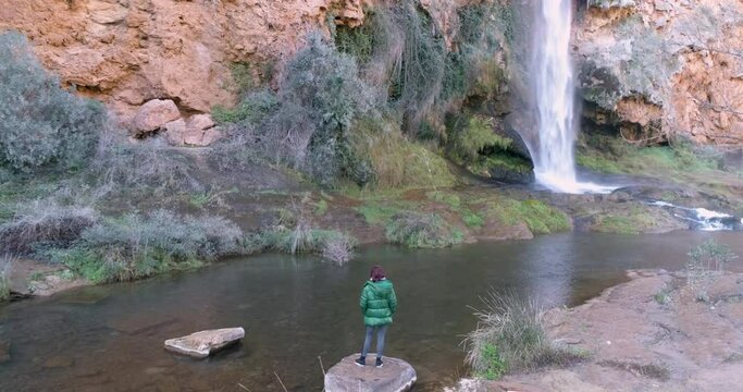 Vuelo a&eacute;reo dron cenital de mujer contemplando cascada de agua en selva