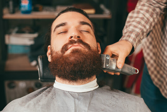 Close up photo of bearded man having haircut.