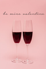 red wine in glasses near be mine valentine lettering on pink