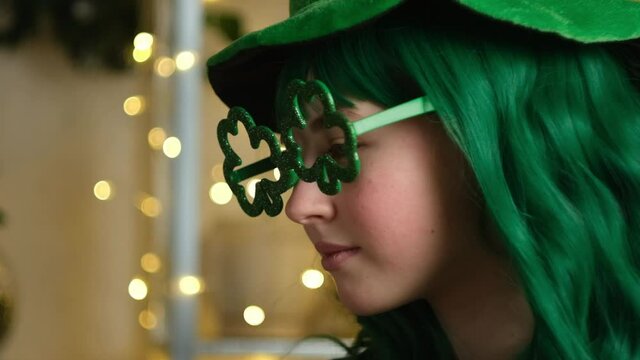 Saint Patrick's day party concept. Beautiful girl with green hair smiling celebrating St. Patrick's day. Closeup portrait.