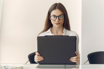 Girl in a office. Woman in a white shirt. Lady use the laptop.