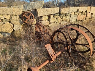 Old farm equipment near stone wall