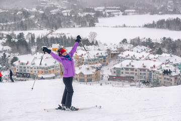Fototapeta Happy skier with arms up in happiness at Mont Tremblant ski resort, Quebec, Canada. View from ski slope. Winter sports woman having fun outdoors. obraz