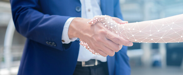 close up on businessman hand shaking with robotic AI hologram to confirm and dealing for business...