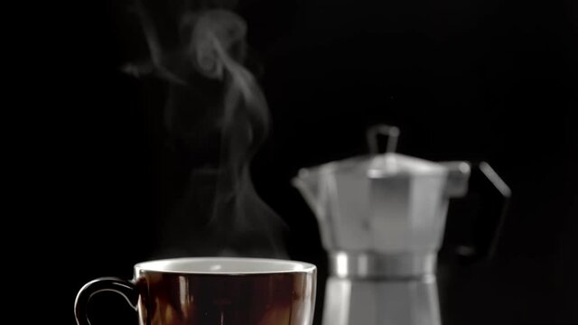 Hot coffee cup and moka pot isolated in dark background