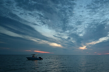 Naklejka premium Boat anchored off Midle Cape Sable beach in Everglades National Park at sunset under dramatic winter cloudscape..