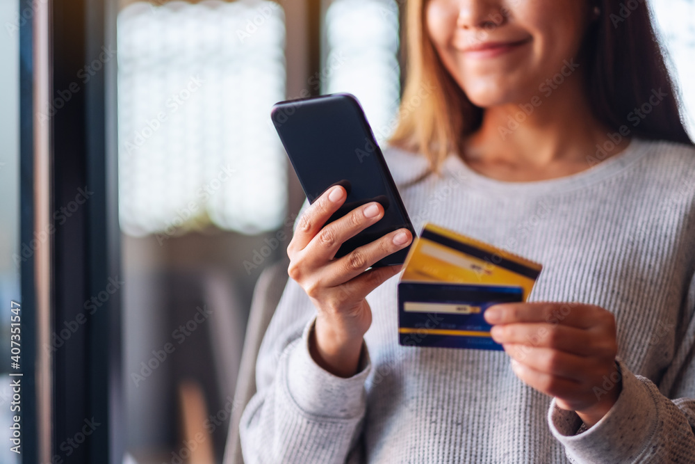 Canvas Prints Closeup image of a woman using credit card for purchasing and shopping online on mobile phone