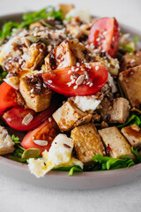 recipe for a healthy diet salad of tofu cheese, tomatoes, eggs, dressing, sesame seeds and seeds. vertical vegetarian food content, close-up, selective focus