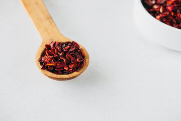 smoked dried pepper slices in wooden spoon, paprika spice on white background. food blog content, selective focus