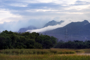 Obraz premium High voltage transmission towers on a hill In the morning light, fog down between Mae Moh valley, Lampang.