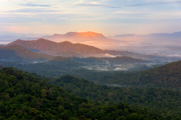 Beautiful mist over green forest on mountain, Aerial view sunrise beam red spot over the mountain range at the north of thailand, Beauty rainforest landscape with fog in morning.