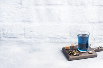 Thai blue tea anchan of buds klitoria Ternate in a glass cup, grey concrete background. Copy space.