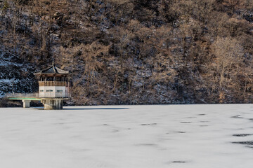 Oriental gazebo and walkway jutting out on frozen lake.