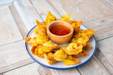Deep fired Chinese Thai style wonton with minced pork and sweet and sour sauce in ceramic dish.