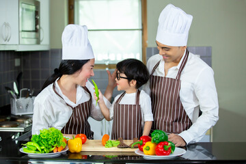 Happy smiling young Asian family with preschool kids have fun cooking breakfast meal in modern kitchen home in the morning. 