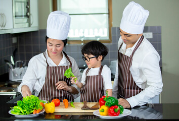 Happy smiling young Asian family with preschool kids have fun cooking breakfast meal in modern kitchen home in the morning. 