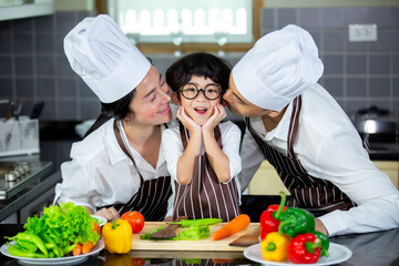 Happy smiling young Asian family with preschool kids have fun cooking breakfast meal in modern kitchen home in the morning. 