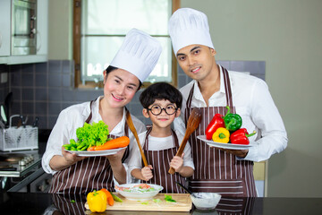 Happy smiling young Asian family with preschool kids have fun cooking breakfast meal in modern kitchen home in the morning. 