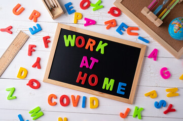 `Work at Home` words on a modern board on a white wooden surface, top view. Overhead, from above, flat lay.