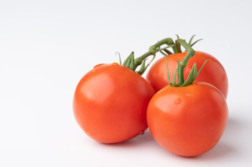Fresh tomatoes on a green stem on white