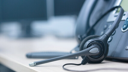 close up on headset with telephone devices at office desk for customer service support concept