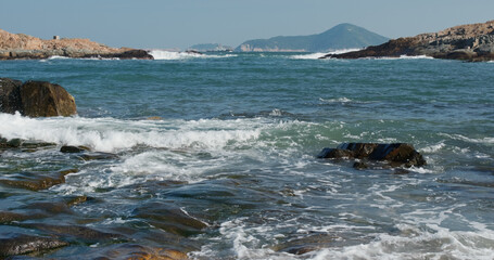 Fototapeta na wymiar Sea waves splash against rock on island
