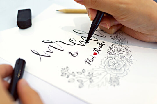 Close up female hand writing with brush pen. Hand lettering process.