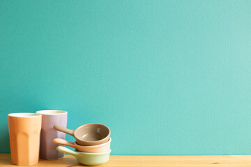 Colorful cups and bowls on wooden table. mint green background
