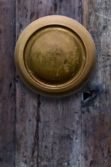 Close up photo of old round antique door knob on gray weathered wooden door. Copy space.