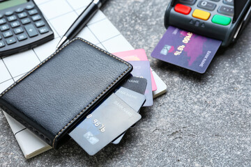 Wallet and credit cards, payment terminal and notebook on grey background