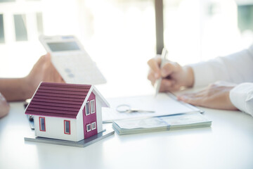 Home model. Hand signing on contract after the real estate agent explains the business contract, rent, purchase, mortgage, a loan, or home insurance to the buyer