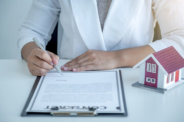Hand signing on contract after the real estate agent explains the business contract, rent, purchase, mortgage, a loan, or home insurance to the buyer
