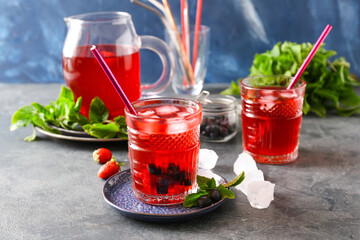 Jug and glasses of tasty cold tea on dark background