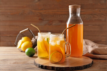 Bottle and mason jars of tasty cold tea on wooden background