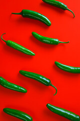 green chilli serrano peppers isolated on red background