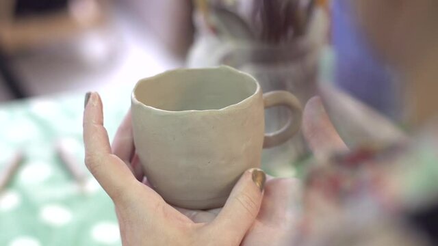 An artisan girl looking at her handmake ceramic mug.