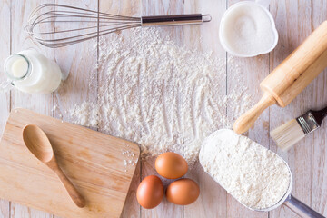 Homemade flour recipes (Eggs, flour, milk, sugar) on a wooden table, view from above