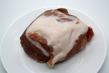 Piece of pork on a plate on a white background.
