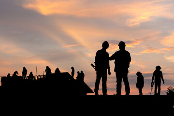 Fototapeta na wymiar Silhouette of Engineer and worker on building site, construction site at sunset in evening time