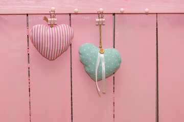 Two hearts made fabric against background of pink wooden wall made of boards. Concept for love of man and woman, Valentine's day, wedding. Copy space, place for your text
