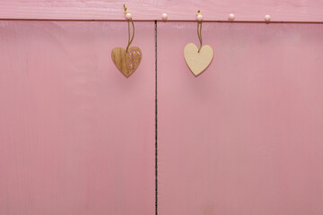 Two small hearts made of wood hang ropes on pink background. Copy space, place for your text. Valentin's day concept, love, wedding