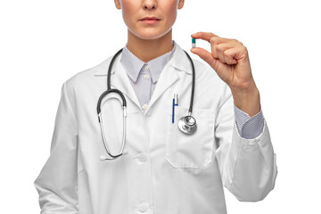 medicine, profession and healthcare concept - close up of female doctor with stethoscope holding pill over white background