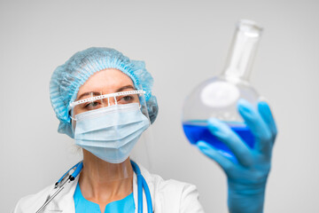 Woman scientist holding laboratory flask with chemical liquid, gray background