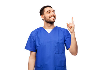 healthcare, profession and medicine concept - doctor or male nurse in blue uniform pointing finger...