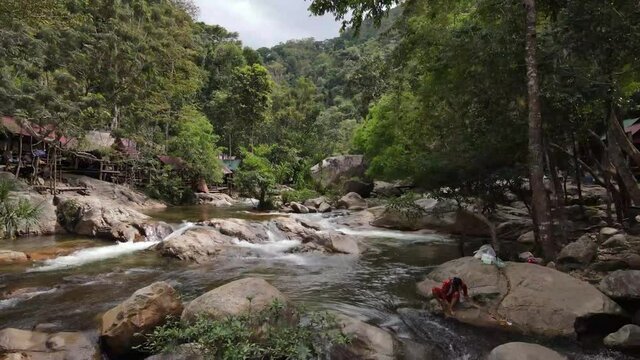 Aerial footage in the middle of the forest in Cardamon mountains above a small waterfall. Camera is moving foward