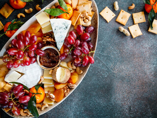 Big cheese board with appetizer assortment. Grape, cheese, nuts, jam and bread.