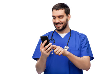 medicine, healthcare and technology concept - happy smiling doctor or male nurse in blue uniform with stethoscope using smartphone over white background